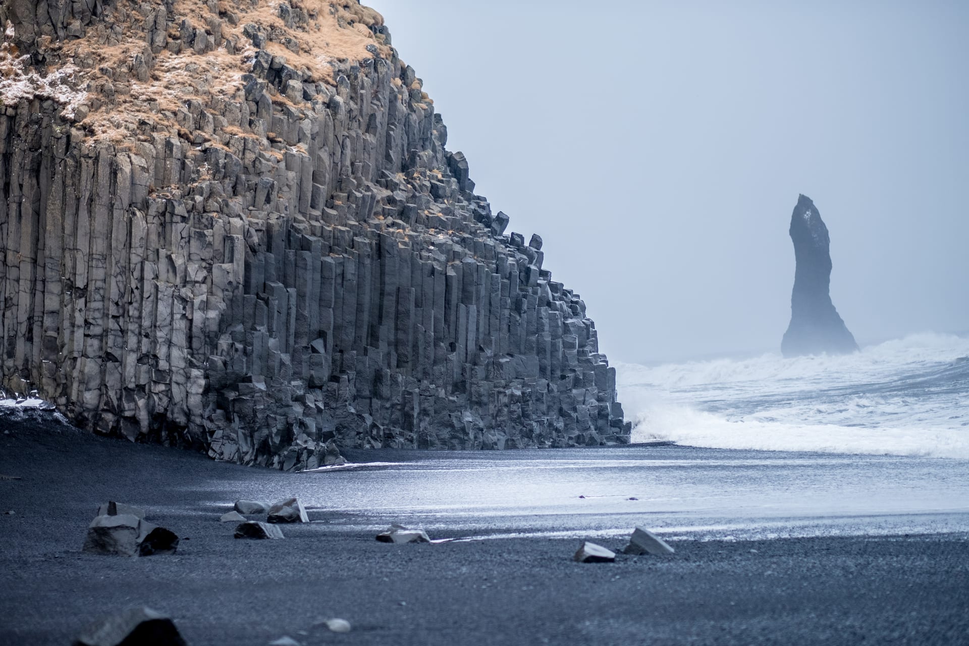 Reynisfjara black-sand beach on Iceland's south coast — basalt columns and the Reynisdrangar sea stacks rising from the surf
